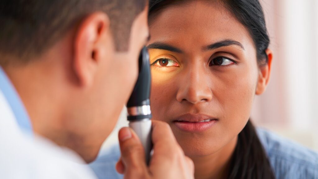 Oftalmólogo examinando posible desprendimiento de retina con oftalmoscopio en consultorio especializado ubicado en Santiago del Estero (Argentina)